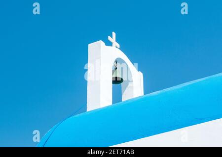 Una campana sulla cima di una tradizionale cappella greca contro con un cielo blu chiaro sullo sfondo Foto Stock