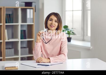 L'insegnante femminile si siede di fronte a una webcam e conduce una lezione online tramite chat video. Foto Stock