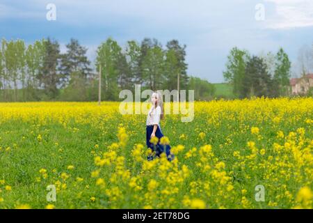 Un bambino in un campo fiorito con fiori gialli. Foto Stock