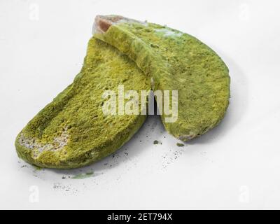 Un pezzo di pane coperto di muffa verde su un isolato di fondo bianco. Foto Stock