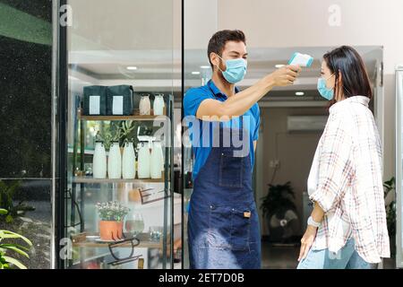 Controllo della temperatura corporea del cliente Foto Stock