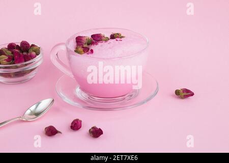 Posare il latte materno in una tazza di vetro sulla superficie rosa Foto Stock