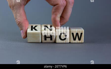 Conoscere il simbolo. L'uomo d'affari gira i cubi e cambia la parola 'come' a 'sapere'. Splendido sfondo grigio. Spazio di copia. Business e know how concetto. Foto Stock