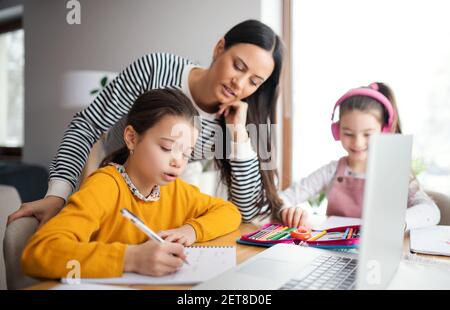 Madre con ragazze della scuola all'interno a casa, a distanza di apprendimento e ufficio domestico. Foto Stock