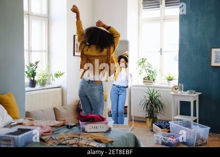 Vista posteriore del guardaroba di smistamento di giovani donne all'interno a casa, concetto di donazione di beneficenza. Foto Stock