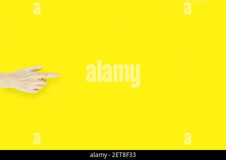 Indice della mano su sfondo giallo, che mostra o punta a qualcosa di invisibile. Foto Stock