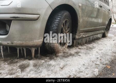 Primo piano auto parcheggiata sulla strada in primavera con un sacco di ghiaccioli. Foto Stock