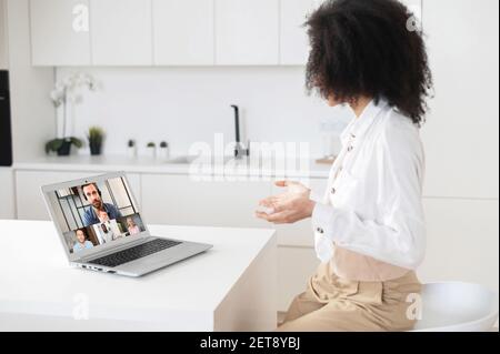 Team di colleghi coinvolti nella videoconferenza con webcam, guidato da un amministratore delegato maschile maturo, brainstorming, revisione dei report online. Giovane donna che chiacchiera a distanza con i colleghi utilizzando il laptop, rimanendo a casa Foto Stock