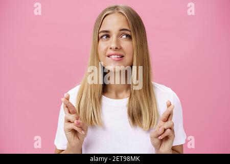 Donna che ha sogno desiderio di venire vero traversare le dita per buona fortuna, facendo desiderio mordere labbro inferiore mentre daydreaming su cosa vuole acquistare Foto Stock