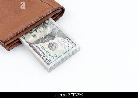 Portafoglio in pelle marrone con dollari isolati su sfondo bianco. Disposizione piatta. Primo piano della foto. Contanti di centinaia di dollari fatture Foto Stock