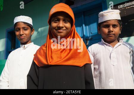 Ritratto di una ragazza musulmana che indossa un hijab con i suoi due fratelli che indossano cappelli Taqiyah ad Alleppey, Kerala, India Foto Stock