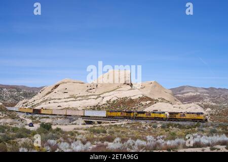 Treno della Union Pacific Railroad che viaggia attraverso il deserto del Mojave mostrato contro le Mormon Rocks nel passo Cajon. Foto Stock