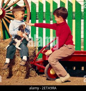 I PICCOLI FRATELLI DEGLI ANNI '60 SUONANO UN RAGAZZO CHE SI SIEDE SULLA BALLA DI FIENO TENENDO IL CUCCIOLO DI BEAGLE PIÙ VECCHIO IN CAMICIA ROSSA SEDUTA SUL CARRO CON RECINZIONE VERDE - KD2026 GRD001 HARS VEICOLO GIOVANILE AMICO FIENO LAVORO DI SQUADRA GIOIA STILE DI VITA FRATELLI RURALE SALUBRITÀ HOME VITA TRASPORTO COPIA SPAZIO AMICIZIA MEZZA LUNGHEZZA PERSONE SIEDONO ALLEVANDO MASCHI FRATELLI TRASPORTO AGRICOLTURA STRUTTURA FELICITÀ MAMMIFERI BENESSERE BEAGLE CANINE ECCITAZIONE ORGOGLIO PETTING CUCCIOLI SIMILI ANIMALI CANI BALLA CANINA CREATURA GIOVANILE MAMMIFERO CUCCIOLO TOGETHERNESS CAUCASICO ETNIA VECCHIO STILE Foto Stock