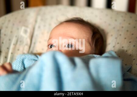 bambino di due mesi sdraiato in un'amaca che guarda askance. occhi graziosi Foto Stock