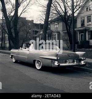 1950 1956 AUTO CADILLAC ELDORADO CONVERTIBILE CON ALETTE POSTERIORI BIANCHE PNEUMATICI PARETE LATERALE LUCI DI CODA RAZZO PARCHEGGIATE SU SUBURBAN STREET - M11682 AMF001 HARS FELICITÀ TESTA E SPALLE QUARTIERE AUTOS PINNE ESTERNE 1956 AUTOMOBILI CADILLAC VEICOLI ELEGANTI ELDORADO PNEUMATICI FLASHY BIANCO E NERO VECCHIO STILE Foto Stock