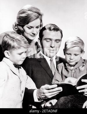 1960 PADRE CHE LEGGE A SUA MOGLIE E A DUE FIGLI DA UN LIBRO LA BIBBIA - R1832 HAR001 HARS VECCHIA MODA 1 GIOVANE COMUNICAZIONE INFORMAZIONI FIGLI FAMIGLIE STILE DI VITA SODDISFAZIONE RELIGIONE FEMMINE SPOSATI FRATELLI SPOSATI SPOSI MARITI COPIA SPAZIO AMICIZIA MEZZA LUNGHEZZA SIGNORE PERSONE ISPIRAZIONE CARING MASCHI FRATELLI CRISTIANI SPIRITUALITÀ PADRI B&W PARTNER FELICITÀ LA SUA RELIGIONE E IL CRISTIANESIMO DADS CHE SIBLING CONNESSIONE ELEGANTE E FEDELE COOPERAZIONE FEDE GIOVANI MAMME SPIRITUALE TOGETHERNESS MOGLI CREDO NERO E BIANCO ETNIA CAUCASICA HAR001 ISPIRATO VECCHIO STILE Foto Stock