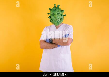 Medico - infermiere in coronavirus mascheramento indossare maschera di lattice - virus covid-19 con braccia incrociate su sfondo giallo. Concetto di coronavirus Foto Stock