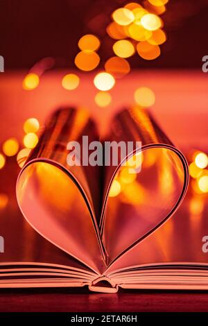 Uno scatto verticale di un cuore creato con le pagine di un libro su uno sfondo chiaro bokeh Foto Stock
