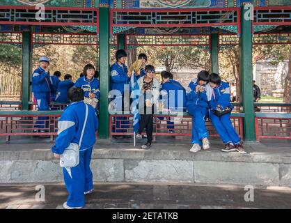 Pechino, Cina - 29 aprile 2010: Palazzo d'estate. Gruppo scolastico di adolescenti in pantaloni blu e gilet appendere insieme sotto una galleria scolpita e dipinta. Foto Stock