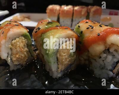 Un primo piano di diversi tipi di sushi con tonno, avocado, granchio, semi di sesamo Foto Stock