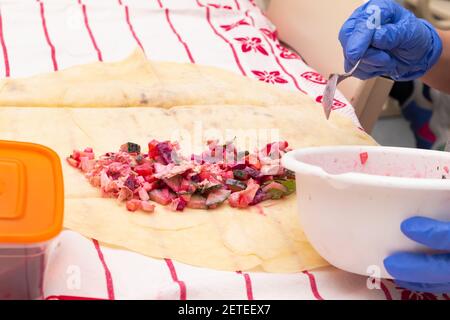 cucina shawarma in una scuola di lezione di lavoro. verdure in pita pane. parti di mani da vicino. fuoco selettivo Foto Stock