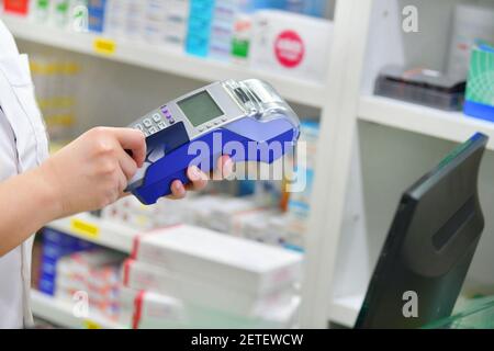 Fare acquisti, Pagare con una carta di credito e utilizzando un terminale su molti scaffali medicinali in background farmacia. Foto Stock