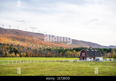 Architettura del paesaggio con generatori eolici per trasformare l'energia eolica in energia elettrica energia sulla cima di una collina coperta di autunno colorato acero alberi e un campo Foto Stock