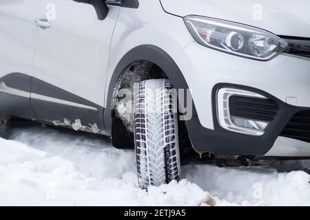 Un frammento della parte anteriore di un SUV con fari, paraurti anteriore, fanali antinebbia su una strada invernale. Condizioni di guida invernali su una strada innevata Foto Stock