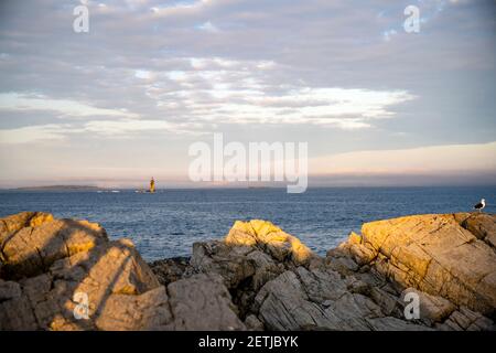 Faro illuminato dal sole che tramonta su un promontorio roccioso Sullo sfondo di un cielo nuvoloso sull'Atlantico Costa a Portland, Maine New Engla Foto Stock