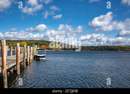 Paesaggio con una barca a motore ormeggiata a piacere in legno pier su un lago pittoresco con colorata foresta di acero deciduo Sulla riva opposta in Main i Foto Stock