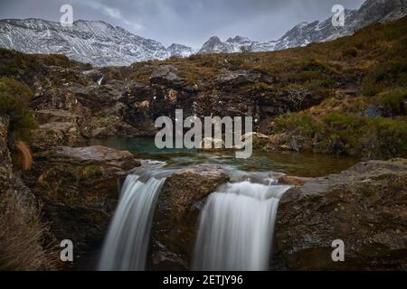 doppia cascata con acqua turchese tra idilliaco paesaggio di montagne Con neve- piscine fairy - Skye Island - Scozia - Regno Unito Foto Stock