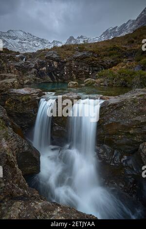 verticale lunga doppia cascata con acqua turchese tra paesaggio idilliaco Di montagne con neve- piscine fairy - Isola di Skye - Scozia - Regno Unito Foto Stock