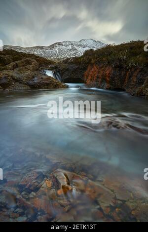 Acque turchesi e trasparenti con rocce e acque setose. Scogliere rosse e montagne di pinne - piscine fairy - Skye Island - Scozia - UK Foto Stock