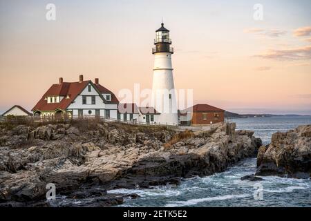 Faro illuminato dal sole che tramonta su un promontorio roccioso Sullo sfondo di un cielo nuvoloso sull'Atlantico Costa a Portland, Maine New Engla Foto Stock