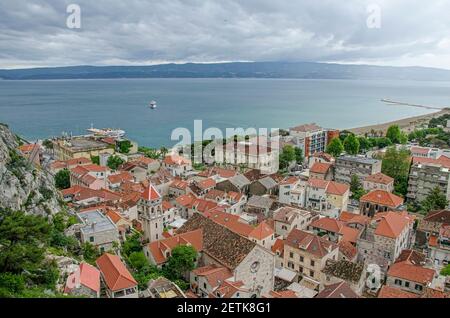 Vista dei tetti rossi tra montagna e mare nella città di Omis, Croazia, dove il fiume Cetina incontra il Mare Adriatico. Vista della piccola città situata tra r Foto Stock