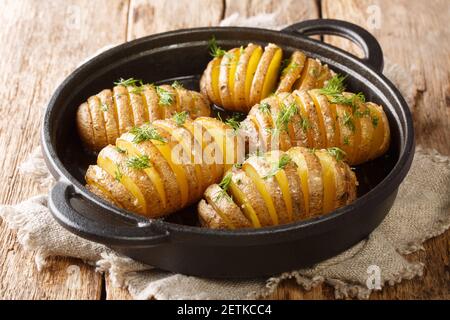 Ricetta classica patate Hasselback primo piano su una padella sul tavolo. Orizzontale Foto Stock