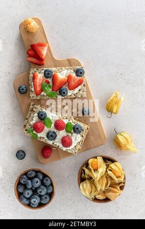 Avena di segale croccante con formaggio di cottage, foglie di menta, fragole fresche e mirtilli. Snack sano. Foto Stock