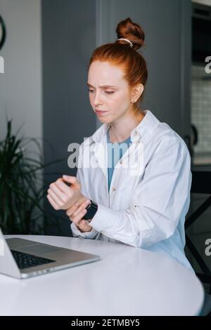 Giovane donna d'affari che soffre di testa rossa che ha dolore al polso durante il lavoro sul computer portatile Foto Stock