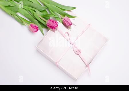 Confezione regalo con cuori di dolci al cioccolato e tulipani su sfondo bianco. Deserto per San Valentino Foto Stock