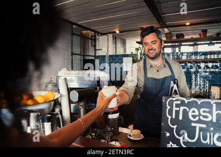 bel barrister maschile che serve una donna appena fatto caffè caldo in caffè funky Foto Stock