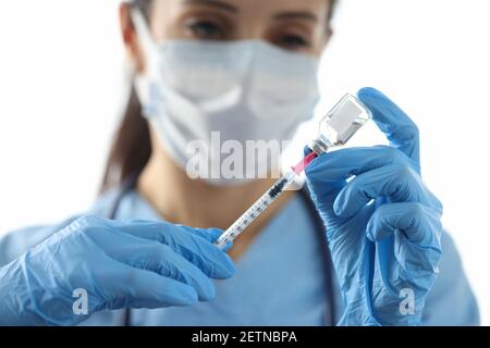 Medico che aspira il medicinale nella siringa dalla chiusura del flaconcino Foto Stock