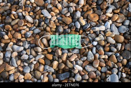 Brighton UK 2 marzo 2021 - UNA maschera di faccia lasciata sulla spiaggia di Brighton nello shingle come il sole comincia a rompere attraverso presto questa mattina: Credit Simon Dack / Alamy Live News Foto Stock