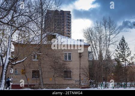 Chelyabinsk, Russia - 14 novembre 2020. Il paesaggio urbano, una vecchia casa bassa e un alto edificio in costruzione contro il cielo. Foto Stock