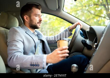 Una mano sul volante e l'altra tenendo una tazza di caffè, nessuna modalità di riposo Foto Stock