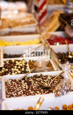 Palline di cioccolato di vari sapori in un negozio con diversi tipi di dolci in scatole con cucchiai self-service. Messa a fuoco selettiva o bokeh Foto Stock