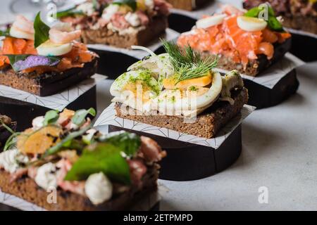 Set di spuntini scandinavi. Smorrebrod. Sandwiches tradizionali danesi aperti, pane di segale scuro con diverse conchetture Foto Stock