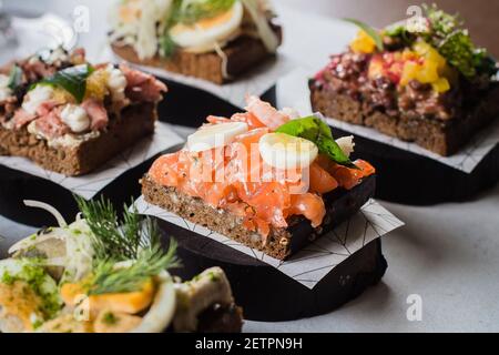 Set di spuntini scandinavi. Smorrebrod. Sandwiches tradizionali danesi aperti, pane di segale scuro con diverse conchetture Foto Stock