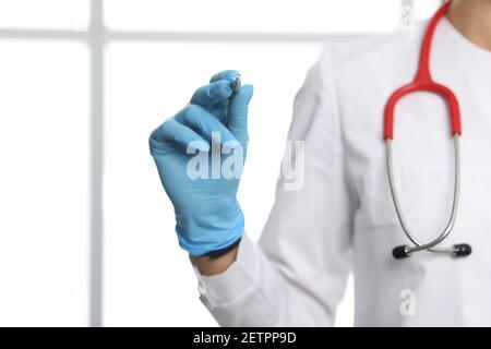 Medico in guanti protettivi che tengono il closeup della penna a sfera Foto Stock