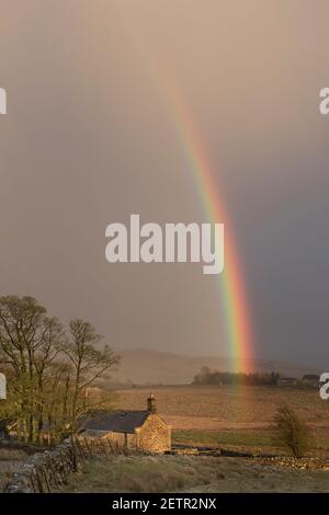 Un arcobaleno si illumina brillantemente durante una tempesta vicino a Steel Rigg e Peel Gap, il Muro di Adriano, Northumberland, Regno Unito Foto Stock