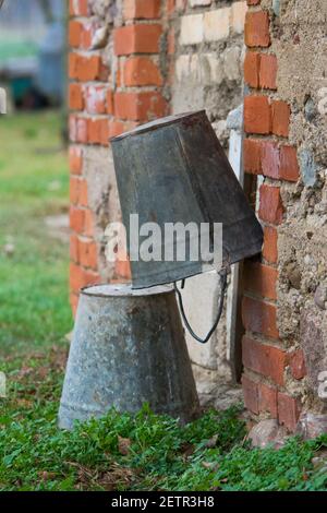 Due secchielli di metallo vecchi vicino al fienile. Vita in campagna. Foto Stock